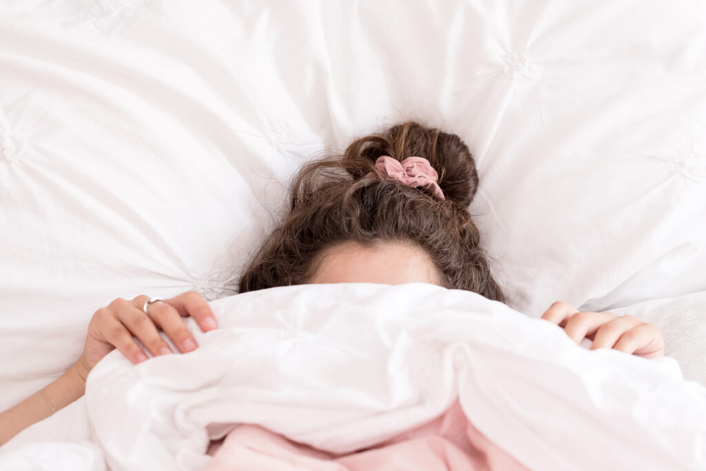 נערה מתבגרת מתחת לשמיכה שלא רואים את פניה כי היא מסתתרת